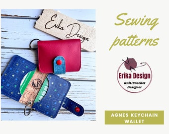 May include: A small keychain wallet featuring a solid magenta exterior and a blue interior with a geometric square pattern. The wallet includes a metal ring, a snap closure with a red button, and a cork-textured card slot. Text reads Erika Design.