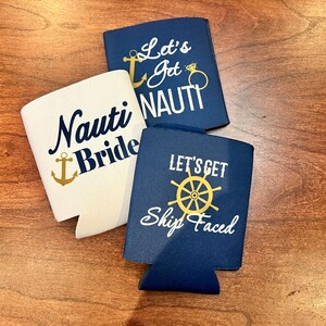 May include: Three navy blue and white drink koozies with nautical-themed text and graphics. One says "Nauti Bride" with an anchor, another says "Let's Get Nauti" with an anchor and ring, and the third says "Let's Get Ship Faced" with a ship's wheel.