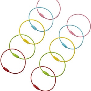 May include: A collection of colorful key rings in various shades, including pink, blue, yellow, green, and red. Each ring features a flexible, coiled wire design with a matching colored screw clasp. The rings are arranged on a white background.