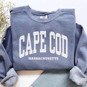 May include: A blue sweatshirt with white text that reads "CAPE COD MASSACHUSETTS".