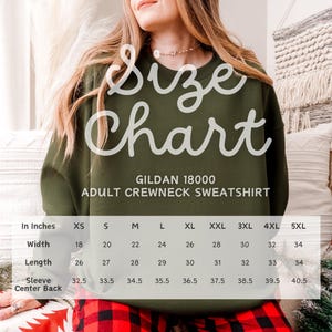 May include: An olive green Gildan 18000 adult crewneck sweatshirt size chart. The chart lists widths from 18 to 34 inches, lengths from 26 to 34 inches, and sleeve centre back measurements from 32.5 to 40.5 inches for sizes XS through 5XL.