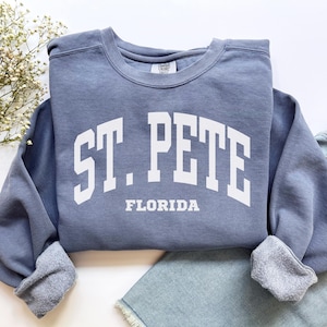 May include: A blue sweatshirt with white text that reads "ST. PETE FLORIDA".