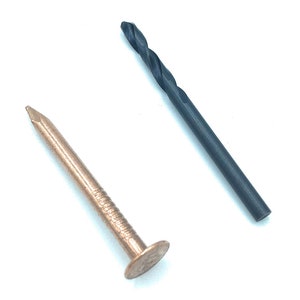 May include: A copper nail with a large head and a black drill bit.