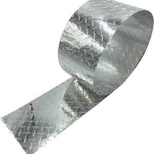 May include: A roll of silver diamond plate aluminum sheet metal. The sheet metal has a textured surface and is rolled up.