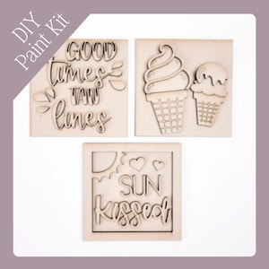 May include: DIY paint kit with three wooden cutouts. One cutout reads "GOOD times TAN lines", another shows two ice cream cones, and the third says "SUN kissed". The cutouts are made of unfinished wood.