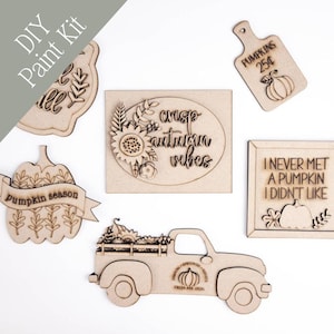 May include: A DIY paint kit featuring wooden cutouts with fall and pumpkin themes. Includes a pumpkin truck, a pumpkin-shaped sign with the text "pumpkin season", and a sign that says "I never met a pumpkin I didn't like".
