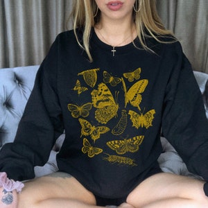 May include: Black sweatshirt with a gold butterfly print. The print features multiple butterflies and other insects in a vintage style.