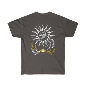 May include: A dark gray t-shirt with a white sun and moon design with a gold eye and floral accents.