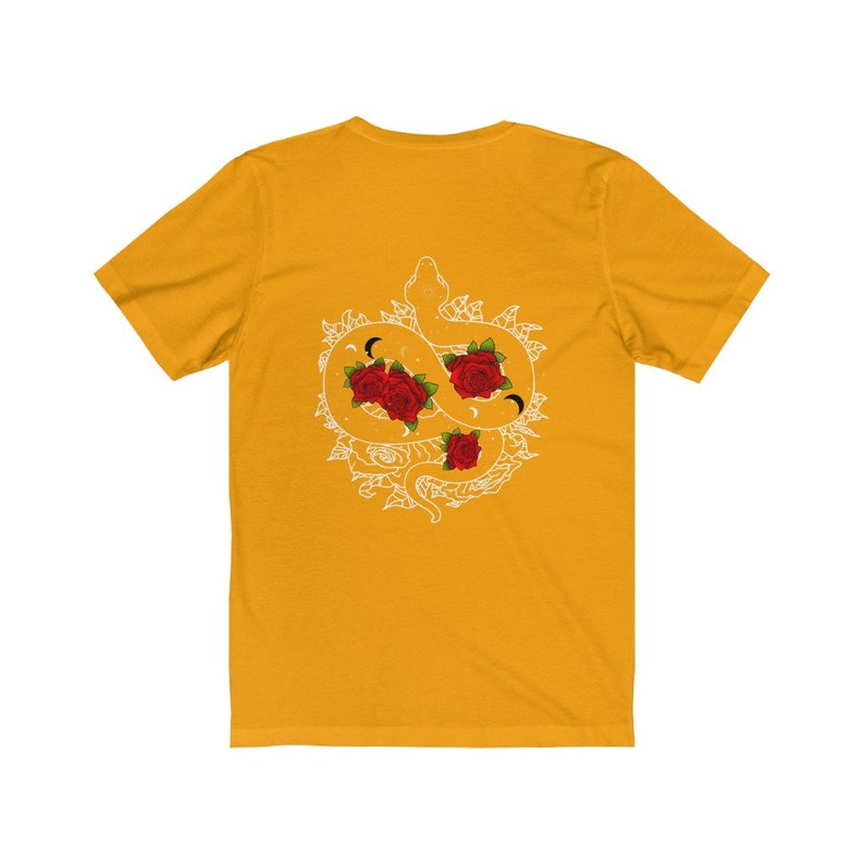 May include: A yellow t-shirt featuring a white graphic of a snake entwined with roses. The snake is curled into a circle and has a crescent moon on its head. The roses are red and have a white outline.
