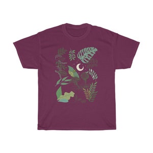 May include: A maroon t-shirt with a graphic design of a crescent moon and various green leaves and branches.