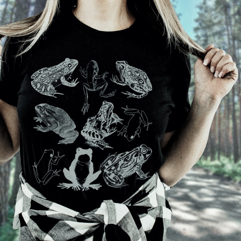 May include: A black t-shirt with a white graphic print of various frogs. The shirt has a plaid pattern on the bottom.