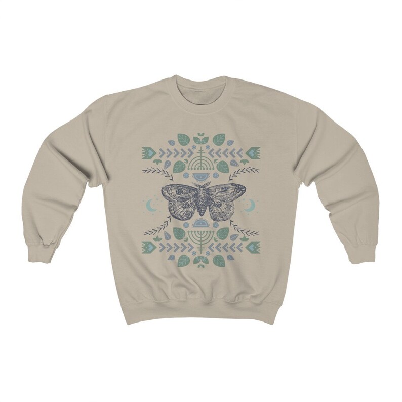 May include: A beige sweatshirt with a blue and green patterned design featuring a moth and geometric shapes.