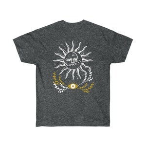 May include: A dark heather grey t-shirt with a white sun and eye design. The sun has a face and is surrounded by white stars and gold floral sprigs.
