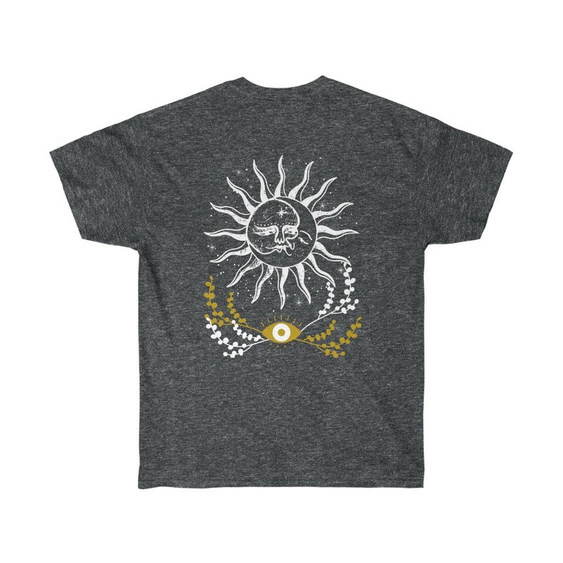 May include: A dark heather grey t-shirt with a white sun and eye design. The sun has a face and is surrounded by white stars and gold floral sprigs.