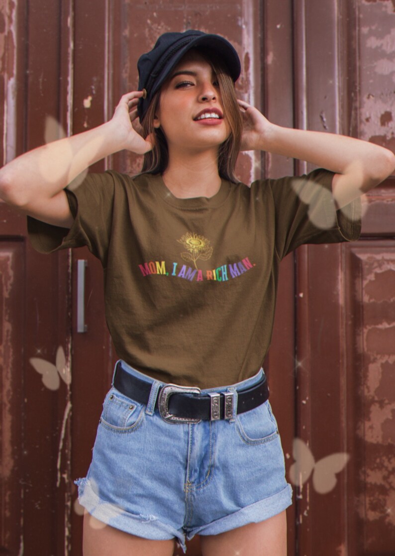 May include: A brown t-shirt with a rainbow sunflower graphic and the text "MOM, I AM A RICH MAN."