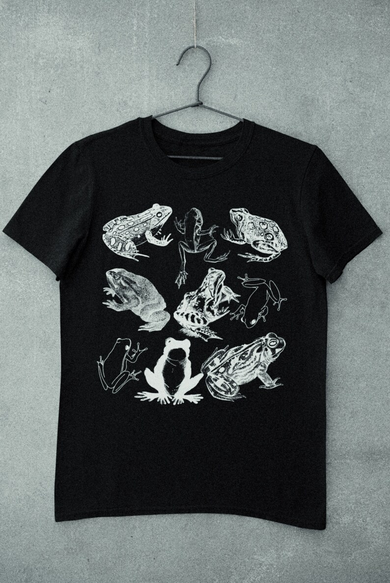 May include: Black t-shirt with a white graphic print of various frogs. The frogs are in different poses and sizes.