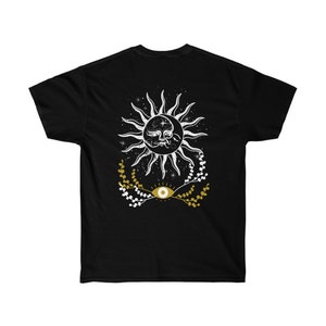 May include: Black t-shirt with a white sun and moon design with a gold eye in the center. The sun and moon are surrounded by white stars and gold floral sprigs.