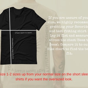 May include: Black t-shirt with white text that reads "A Little Less Judgement, A Little More Love."  The shirt is laid flat and has measurements marked for chest and shoulder width.  The text "Size 1-2 sizes up from your normal size on the short sleeve shirts if you want the oversized look." is also included.