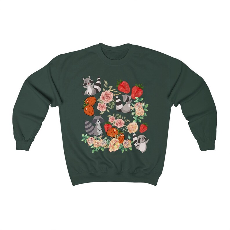 Pu&ograve; includere: Una felpa verde scuro con un motivo di procioni, fragole e fiori. I procioni indossano un fiocco rosa e un fiocco rosso.
