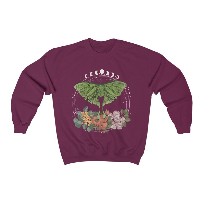 May include: A maroon sweatshirt with a green luna moth design. The moth is surrounded by a circle of white crescent moons and floral accents.