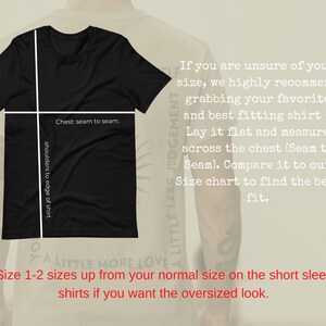 May include: Black t-shirt with white text that reads "A Little Less Judgement, A Little More Love."  The shirt is laid flat and has measurements marked for chest and shoulder width.  The text "Size 1-2 sizes up from your normal size on the short sleeve shirts if you want the oversized look." is also included.