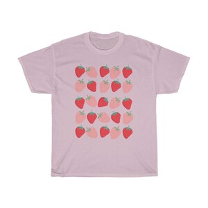 May include: A light pink t-shirt with a repeating pattern of red and pink strawberries.