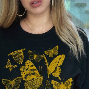 May include: Black sweatshirt with a yellow graphic print of various butterflies.