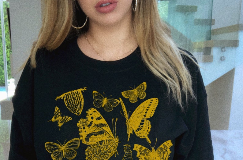 May include: Black sweatshirt with a yellow graphic print of various butterflies.