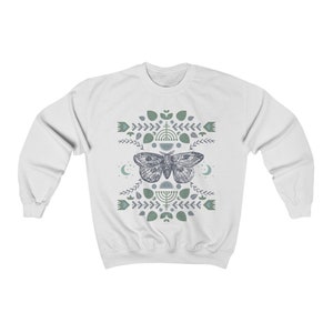 May include: White sweatshirt with a blue and green geometric design featuring a moth and crescent moons.