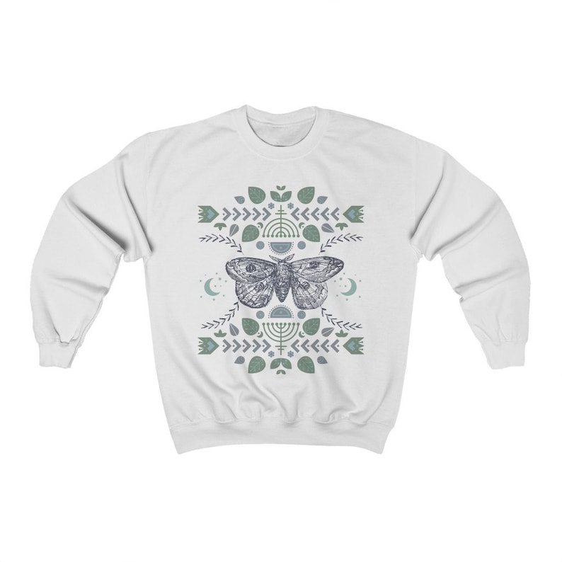 May include: White sweatshirt with a blue and green geometric design featuring a moth and crescent moons.