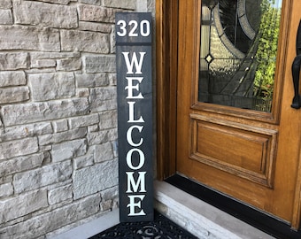 May include: A black wooden welcome sign with white lettering. The sign says "WELCOME" and has the number "320" at the top.
