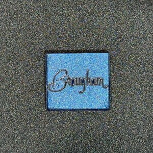 May include: A blue square with the word "Brougham" written in black cursive lettering.