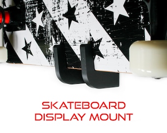 Könnte beinhalten: Schwarzer Skateboard-Wandhalter mit zwei U-förmigen Haken. Das Skateboard hat ein schwarz-weißes Design mit Sternen. Der Text "Skateboard Display Mount" ist unter dem Skateboard gedruckt.