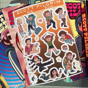 May include: A stack of graphic novels featuring the Scott Pilgrim series. The top book is Scott Pilgrim's Finest Hour, volume 6. The book is red with black and white illustrations. The book is next to a sticker sheet featuring characters from the Scott Pilgrim series. The sticker sheet is on a brown background with a white border. The sticker sheet features characters from the Scott Pilgrim series, including Scott Pilgrim, Ramona Flowers, and Knives Chau.