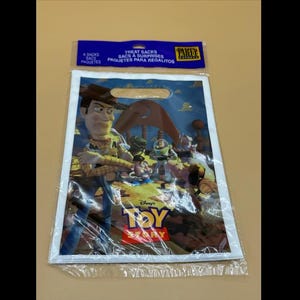 May include: A clear plastic party favor bag featuring characters from the animated film "Toy Story." The bag has a white border and a blue header with text. The bag's design includes Woody, Buzz Lightyear, and the Toy Story logo.