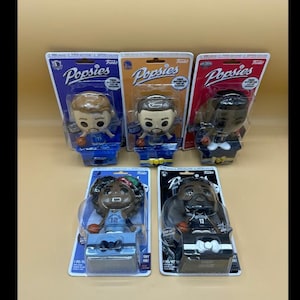 May include: Five Popsies collectible figures in their original packaging. The figures are of various people, each with a unique design. The packaging is a mix of blue, orange, and red, with the Popsies logo visible.