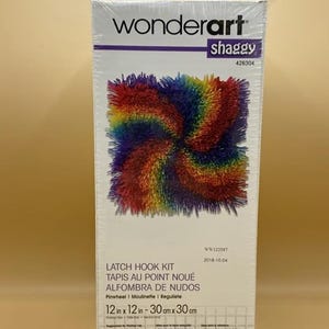 May include: A Wonderart Shaggy latch hook kit. The box features a colorful, swirling design in shades of red, orange, yellow, green, blue, and purple. The kit includes a 12 x 12 inch (30 x 30 cm) rug.