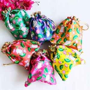 May include: A collection of six colorful drawstring bags. Each bag features a vibrant floral and animal print in shades of green, blue, orange, red, pink, and yellow. The bags have gold-colored drawstrings and decorative trim.