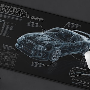 May include: A black rectangular desk mat featuring a white technical blueprint illustration of a 1994 Toyota Supra JZA80. The design includes detailed engine specifications, performance data, and a power and torque curve graph printed in white.