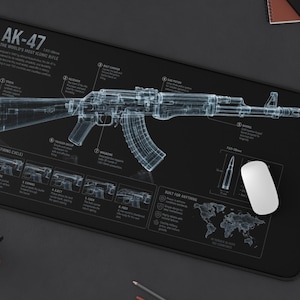 May include: A black rectangular desk mat featuring a white wireframe technical blueprint of an AK-47 rifle. The design includes detailed labels for rifle components, a firing cycle diagram, and a world map graphic printed on the surface.
