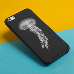 May include: A black phone case with a white jellyfish design. The jellyfish is in the center of the case and has a bell-shaped head and long tentacles.