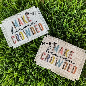 May include: Two burlap patches with frayed edges, one white and one beige, with the text "MAKE heaven CROWDED" in colorful letters with a leopard print pattern.