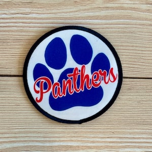 May include: A white round patch with a blue paw print and the word "Panthers" in red lettering.
