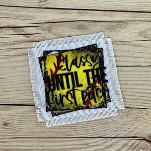 May include: A white canvas with a black and yellow softball design. The text "Classy Until The First Pitch" is printed on the softball.