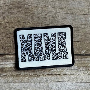 May include: A white patch with a black border featuring the word "MAMA" in large, bold letters. The letters are filled with a black and white leopard print pattern.