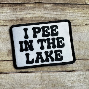 May include: White patch with black text that reads "I PEE IN THE LAKE" in a retro font.