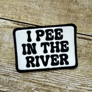 May include: White patch with black text that reads "I PEE IN THE RIVER" in a retro font.