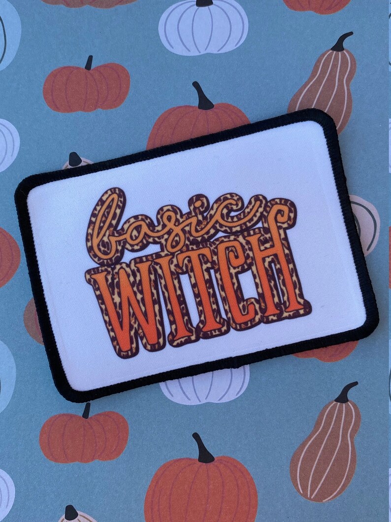 May include: A white patch with black edging features the text "basic witch" in orange and brown leopard print lettering.