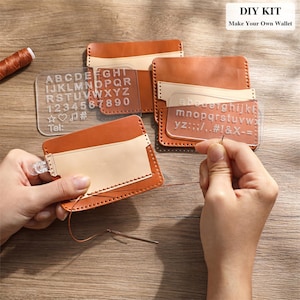 May include: A DIY wallet kit with brown leather pieces, clear acrylic letter and number templates, and a needle with thread. The text "DIY KIT Make Your Own Wallet" is visible. The kit includes the alphabet, numbers, and symbols.