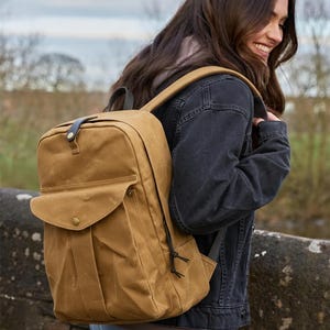 Peut inclure: Un sac à dos de couleur beige avec une poche à rabat et une poignée supérieure. Le sac à dos a une sangle en cuir bleu foncé et une fermeture à cordon. Le sac est fait d'un matériau durable et résistant à l'eau.